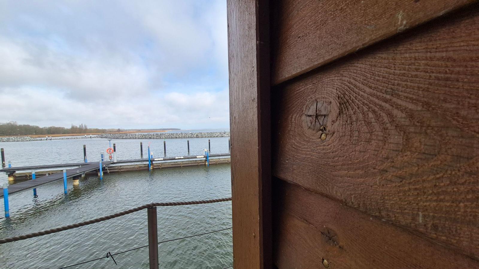 Moderne Holzhäuser mit beleuchteten Fenstern reflektieren sich im Wasser bei Nacht.