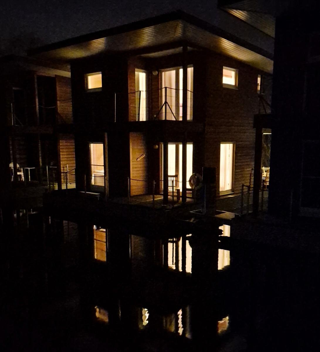 Holzhaus am Wasser mit Schnee und hohem Schilf.