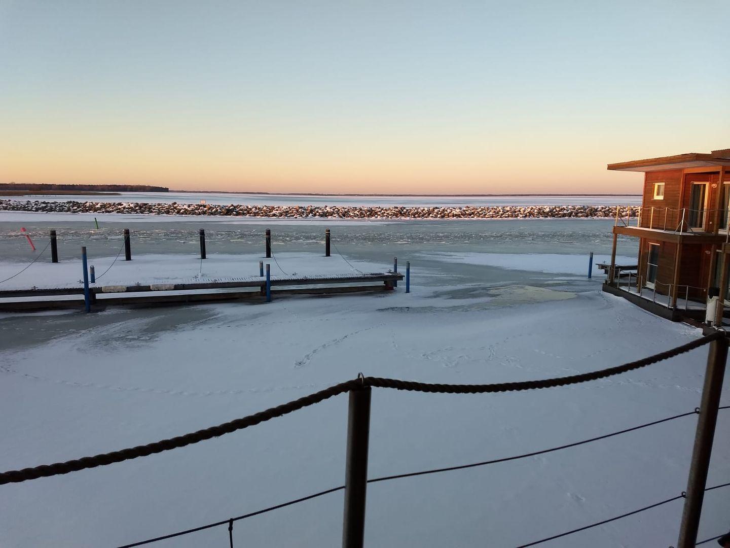 Esszimmer mit runden Tisch, weißen Stühlen und Blick auf Wasser.