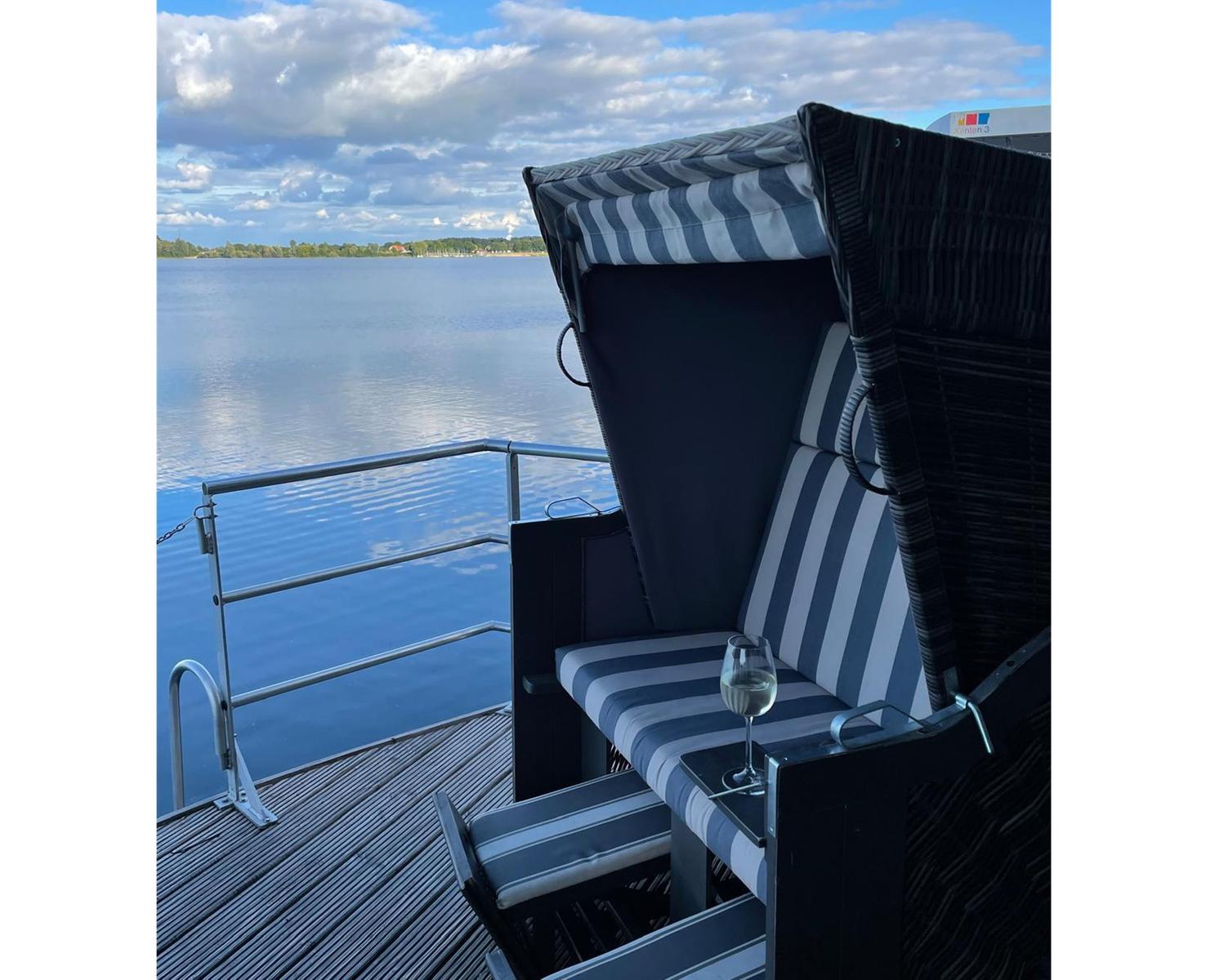 Hochwertiger Strandkorb mit Streifenbezug auf Terrasse mit Blick auf Wasser.