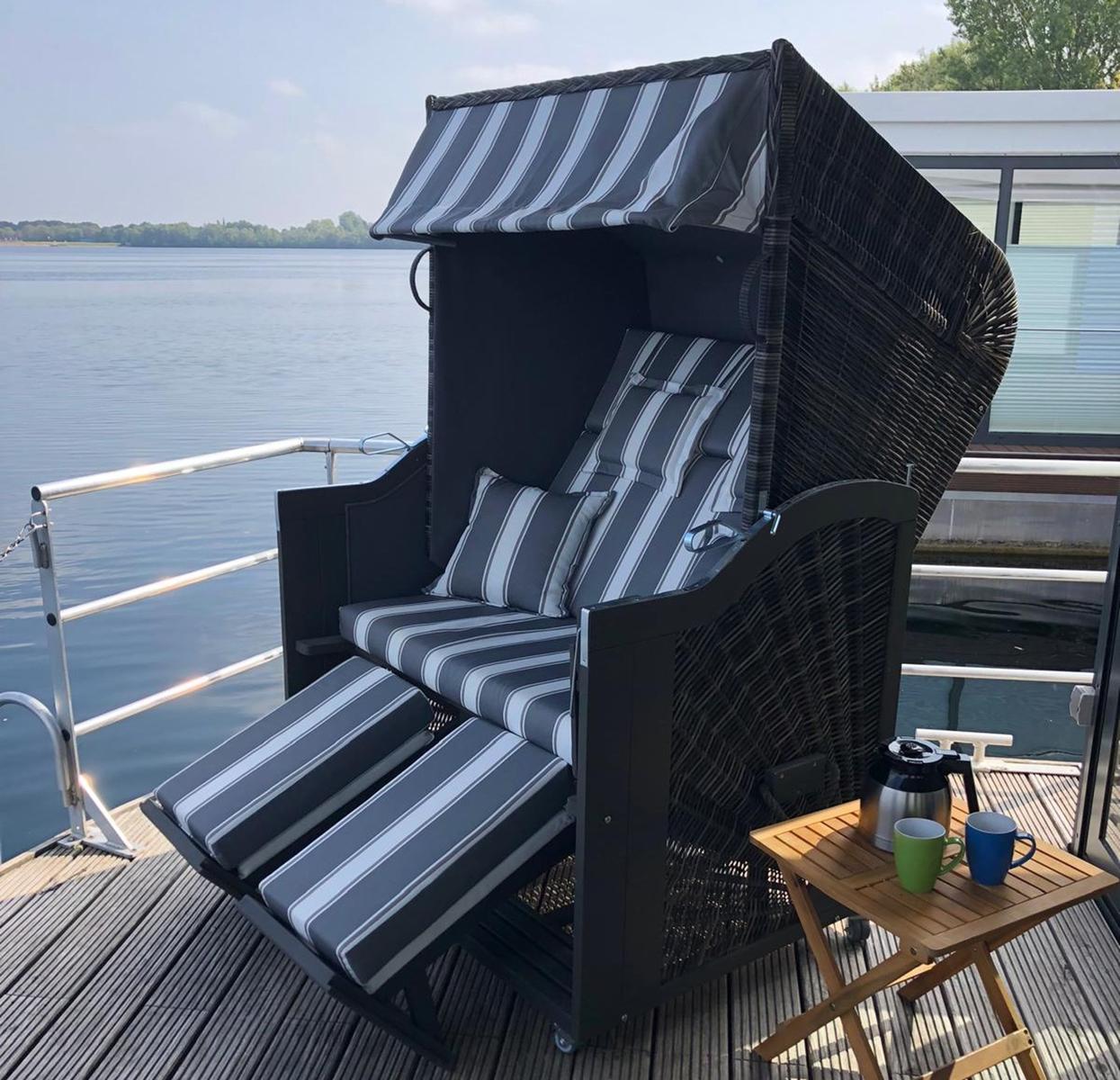 Terrasse mit Tisch und Stühlen am Wasser bei Sonnenuntergang.