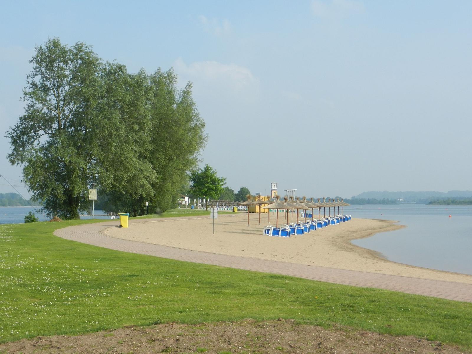 Segelboote liegen am Wasser, hinter ihnen ein Restaurant mit Terrasse.