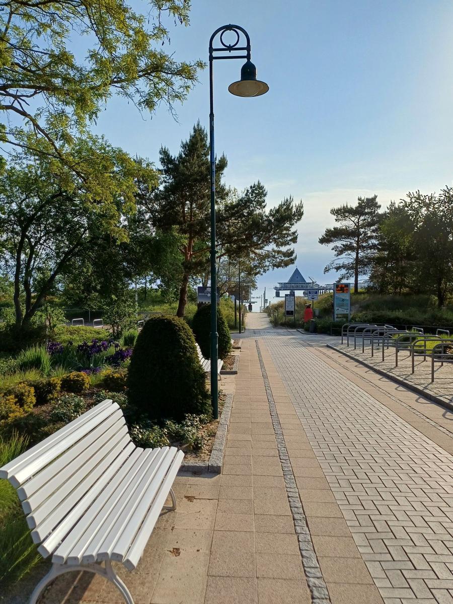 Holzpfosten führen durchs Wasser zu einer Pier mit Pavillon.