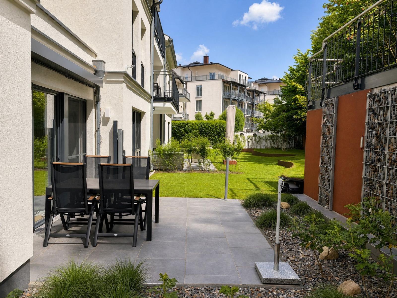 Moderne weiße Villa mit Balkon und Garage an einer gepflasterten Straße.