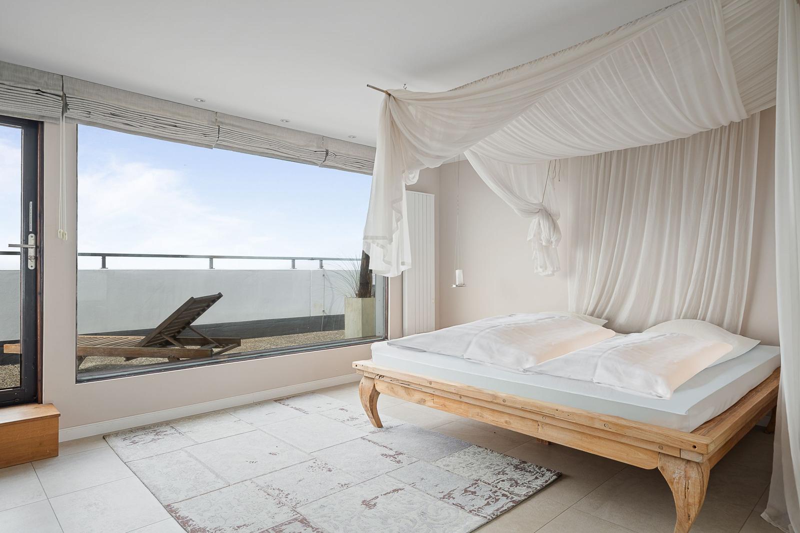 Schlafzimmer mit Doppelbett, Balkon und Holzboden.