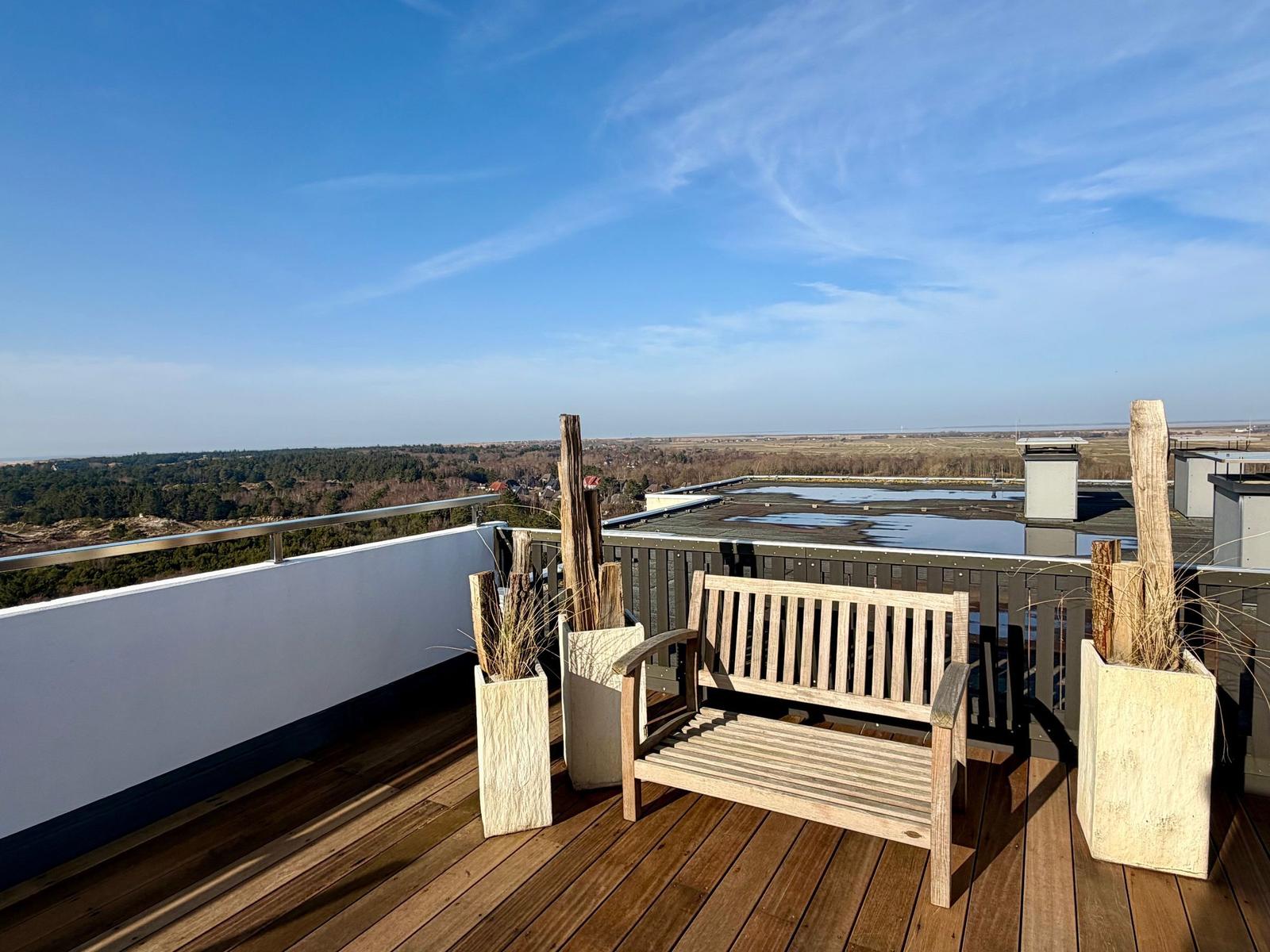 Terrasse mit Holzboden, Liegestühlen und Blick auf die Landschaft.