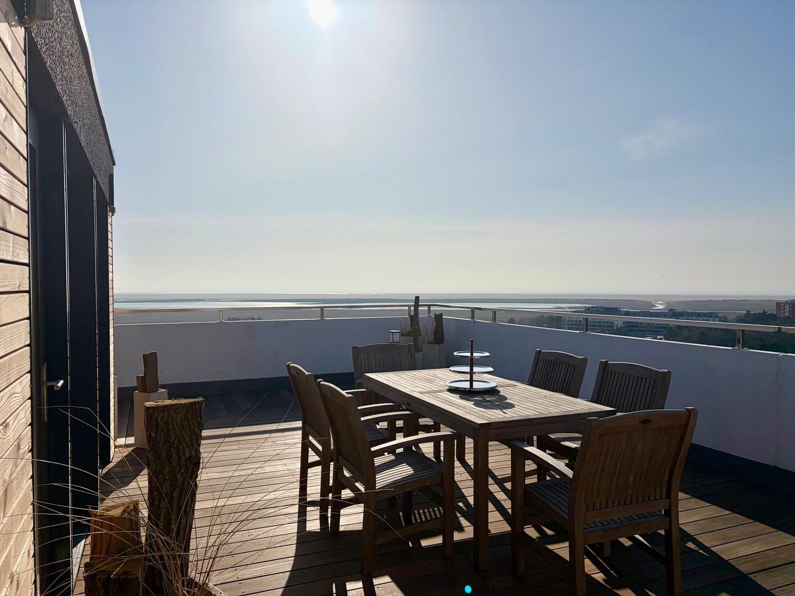 Terrasse mit Holzdielen und Liegestühlen, Blick auf die Landschaft.