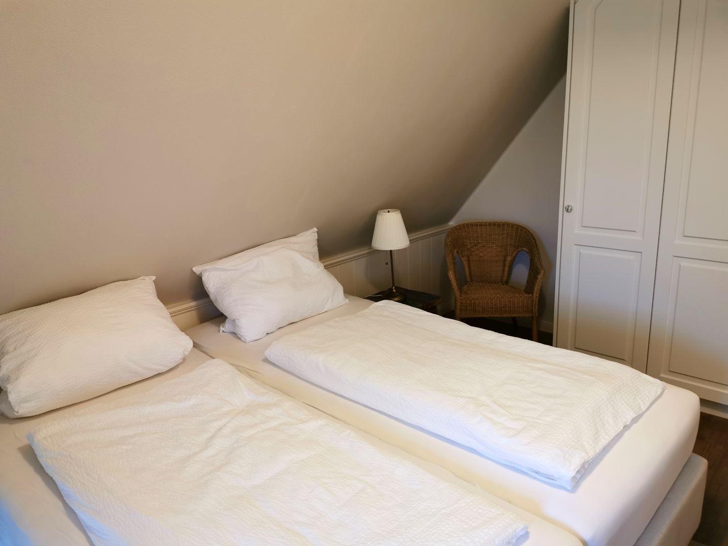 Ein Schlafzimmer mit einem weißen Bett, einem Nachttisch und einer Lampe.