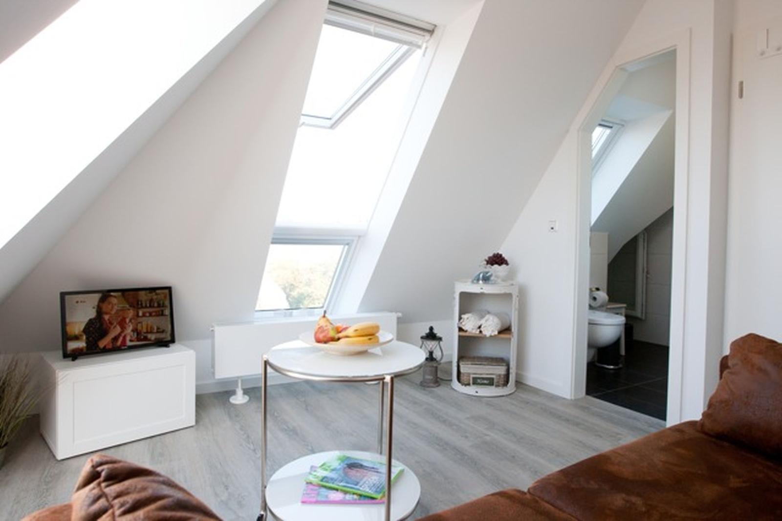 Schlafzimmer mit Doppelbett, blauer Bettwäsche und Fenster mit Blick auf Grün.