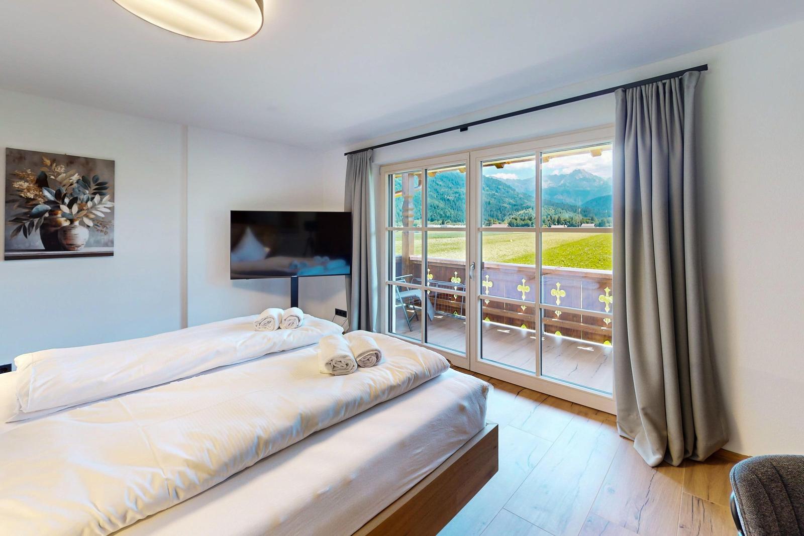 Doppelbett mit weißen Bettwäsche, Holzfußboden und Wandbildern.