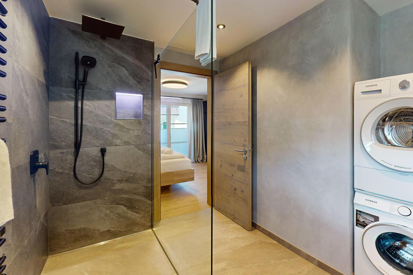 Dusche mit Duschbrause, Handtuchhalter und Steinwand