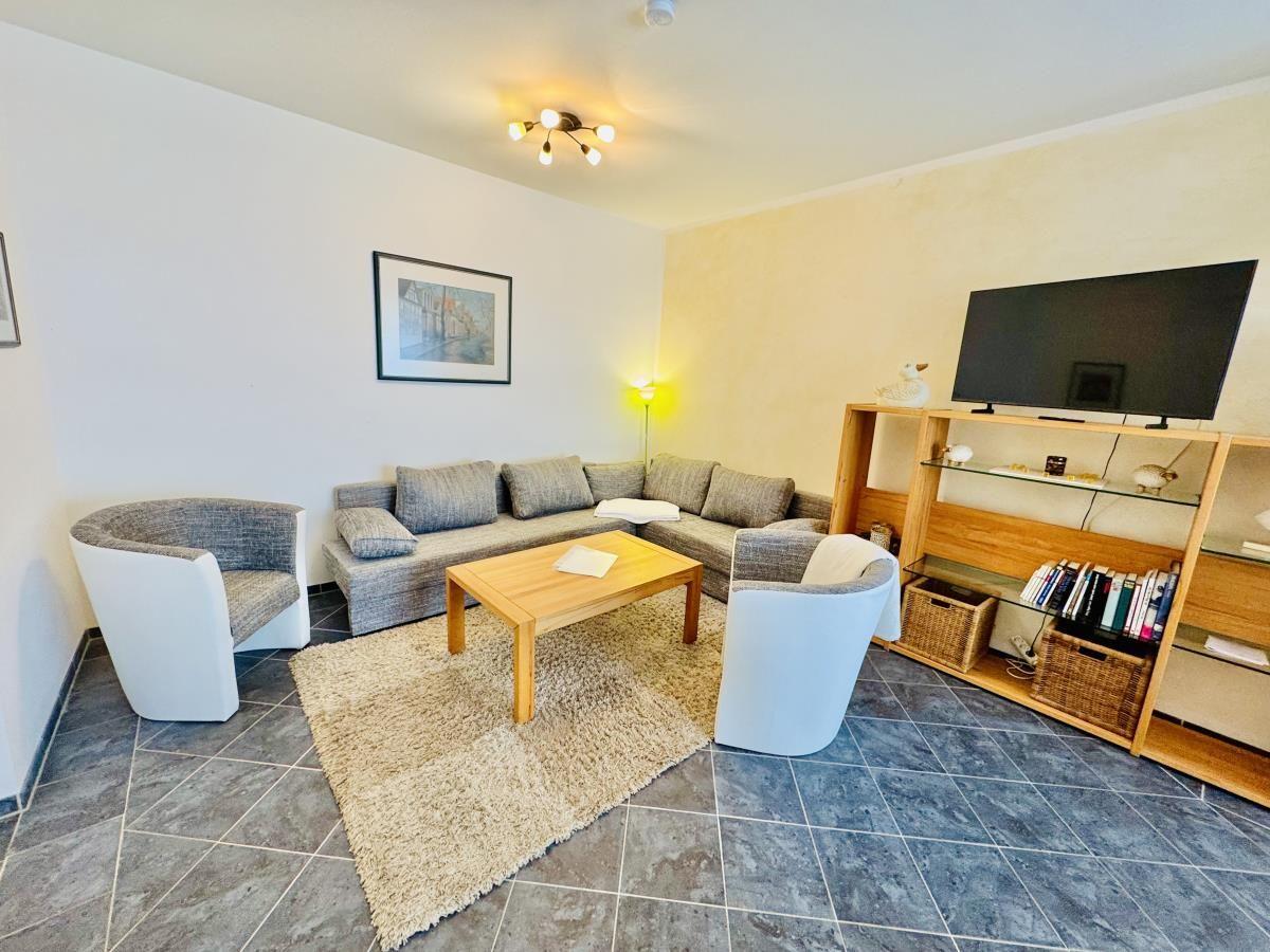 Küche mit Essbereich, Holztisch, vier Stühle und Fenster mit Vorhängen.