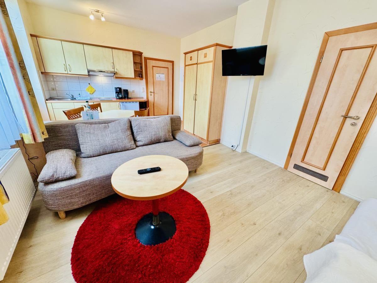 Küche mit Arbeitsplatte, Spüle, Herd und Kühlschrank. Tisch und Stühle im Raum.