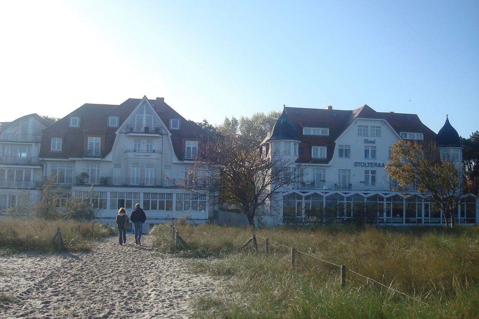 Weißes Mehrfamilienhaus mit Balkonen und Fenstern unter blauem Himmel.
