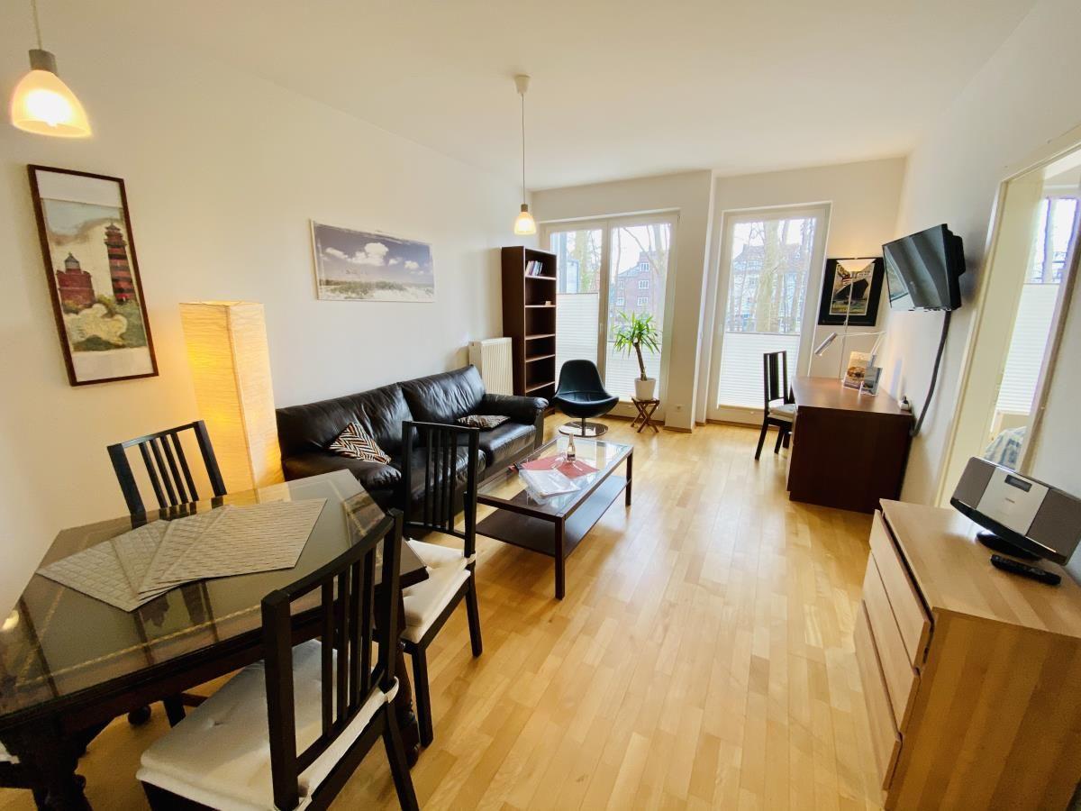 Schwarzes Sofa mit Kissen, Glas-Tisch und Sessel im Wohnzimmer.