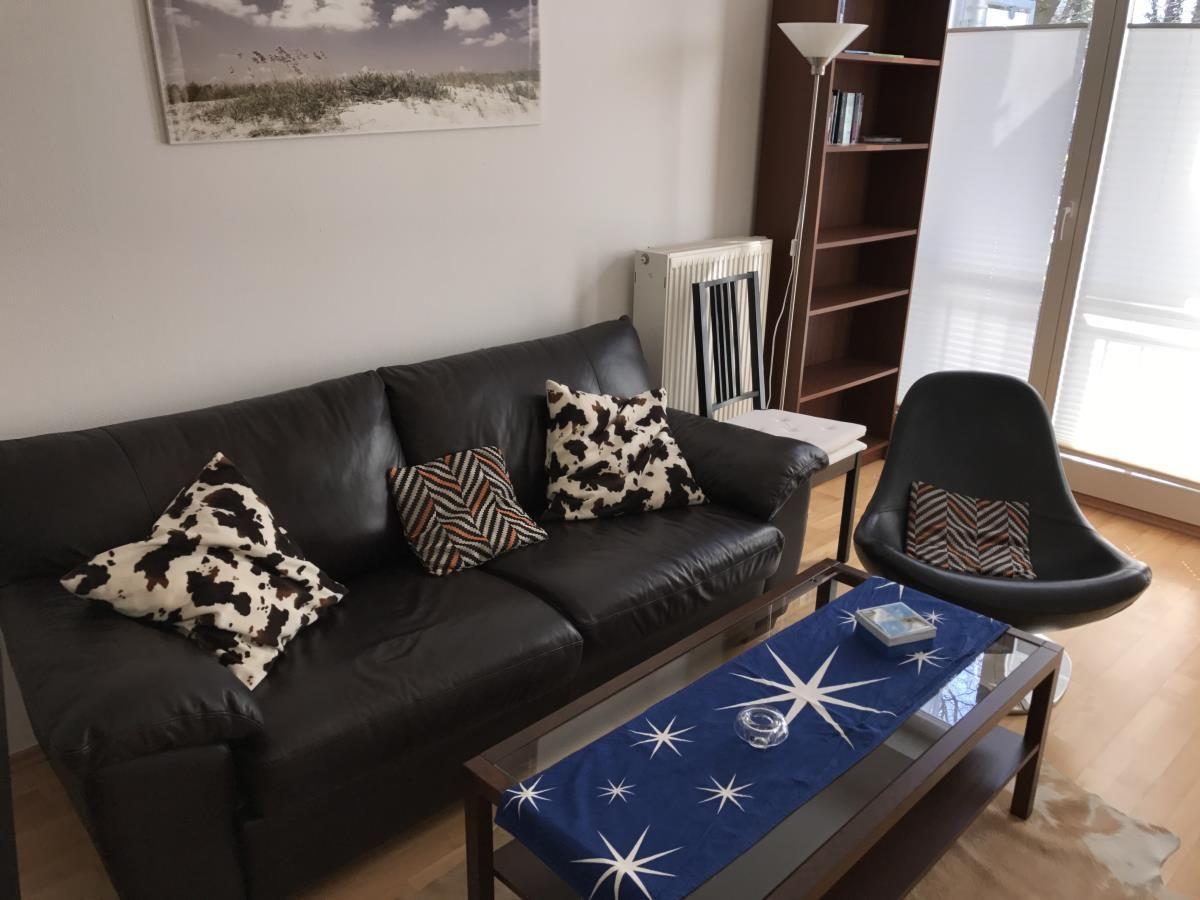 Esszimmer mit Tisch, Stühlen und Sofa. Wandbilder zeigen Leuchttürme.