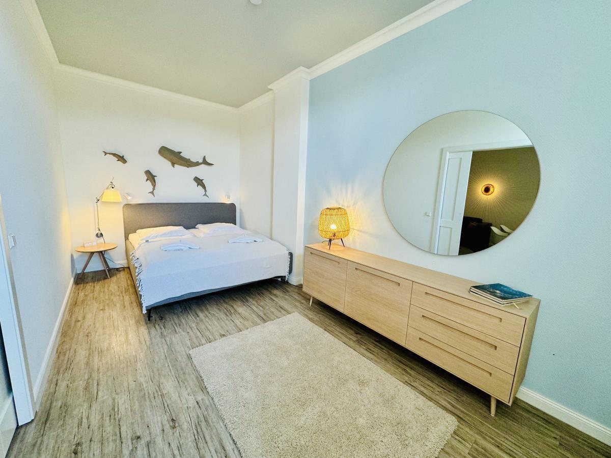Schlafzimmer mit Doppelbett, Fenster, TV und Holzboden.