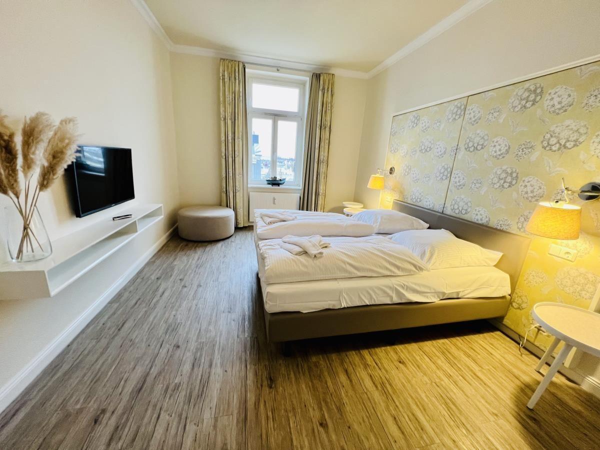 Schlafzimmer mit Doppelbett, Kleiderschrank und Fernseher an der Wand.