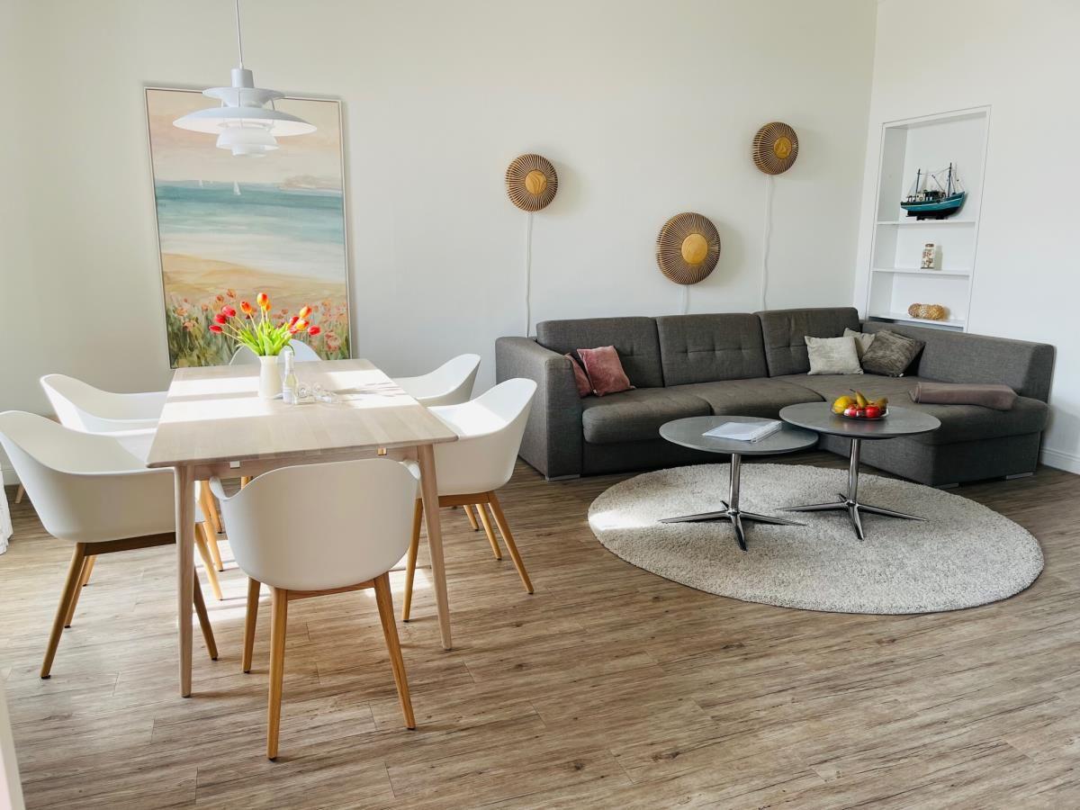 Esszimmer mit Tisch, Stühlen und Fenstern. Holzfußboden und Vorhänge.