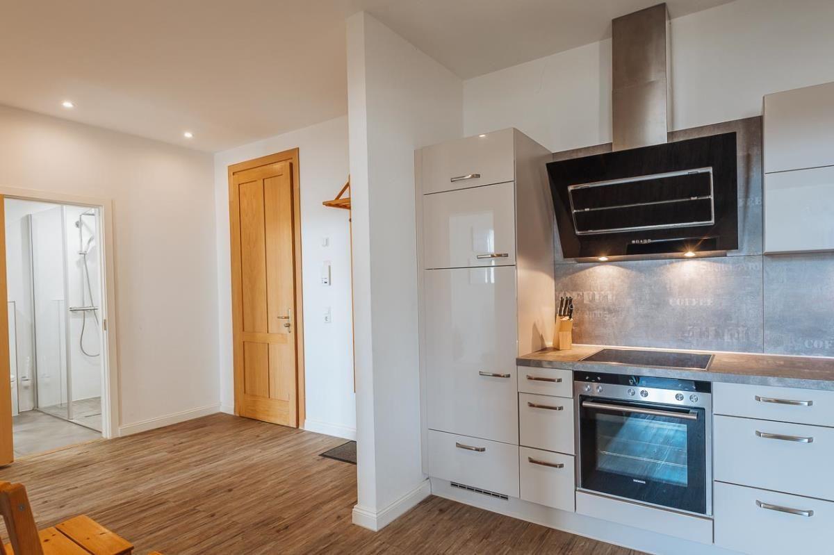 Tisch mit Tulpen, Weinflasche und Gläsern. Im Hintergrund Küche und Wohnzimmer.