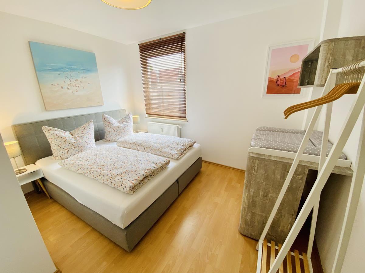 Schlafzimmer mit Doppelbett, Fenster mit Jalousie und Kleiderschrank.