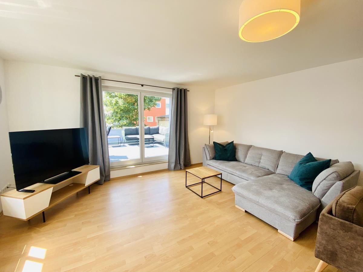 Wohnzimmer mit Sofa, Sesseln und großem Fenster zur Terrasse.