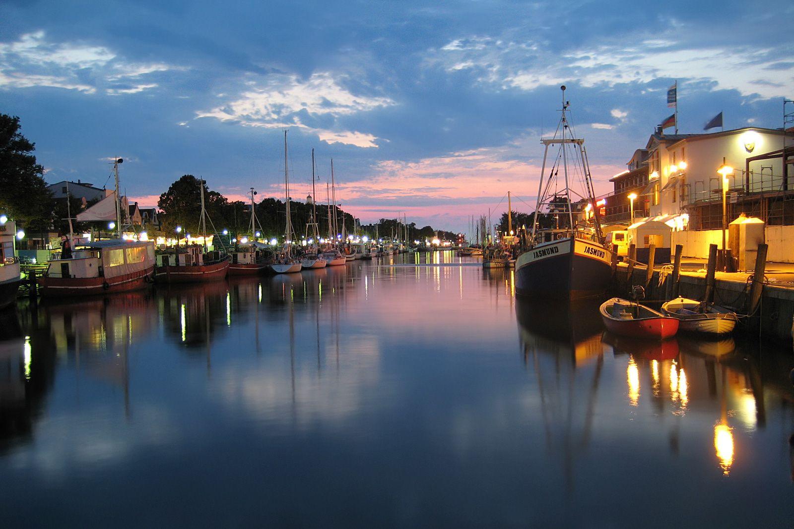 Aerial view of harbor, beach, and town at dusk.