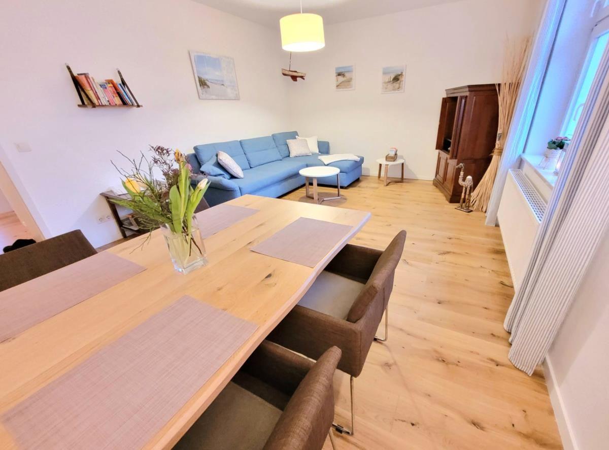 Esszimmer mit Tisch und Stühlen, Wohnbereich mit Sofa und Holzboden.