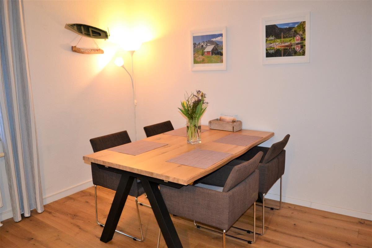 Küche mit weißen Schränken, Edelstahlspüle und Fenster mit Pflanzen.