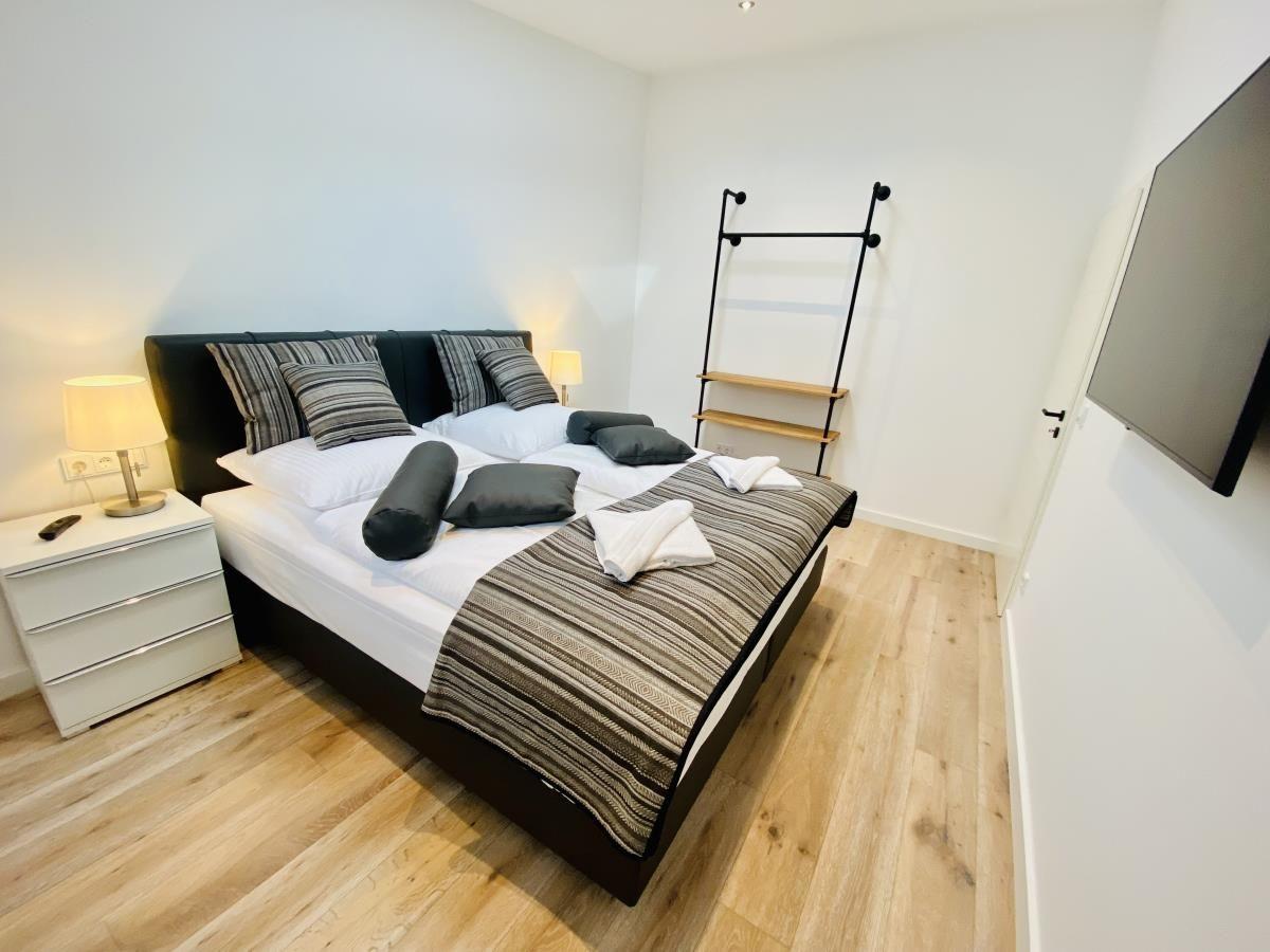 Schlafzimmer mit Bett, Fernseher und Kleiderständer