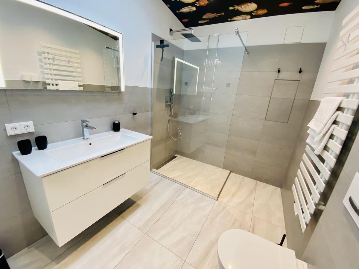 Badezimmer mit Dusche, Toilette und Fischmotiv-Wand