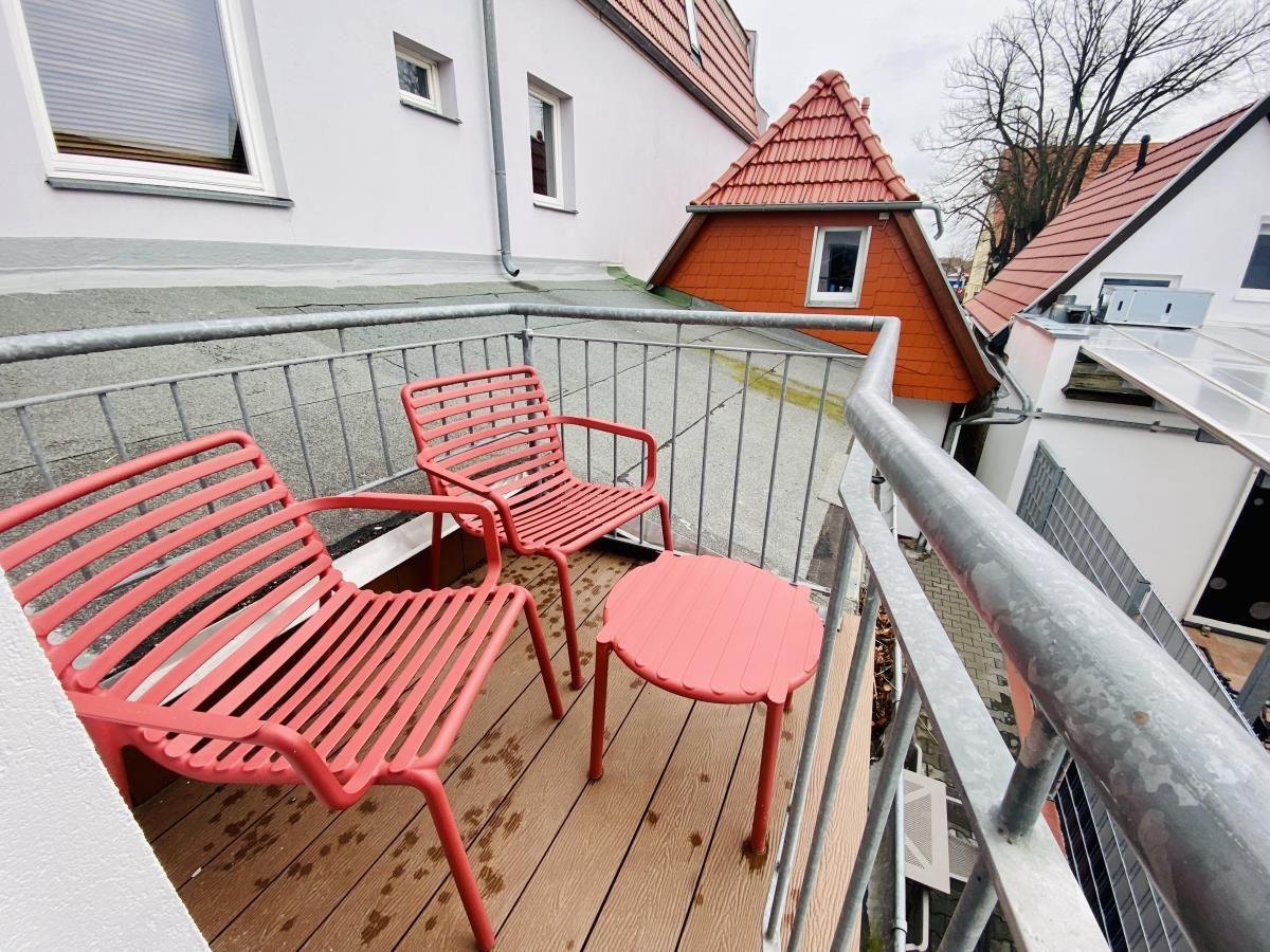 Kurze Straße mit Fachwerkhäusern und Blumenkästen an den Fenstern.