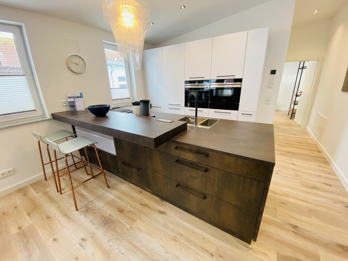 Offener Raum mit Küche, Essbereich und TV. Holzboden und moderne Einrichtung.