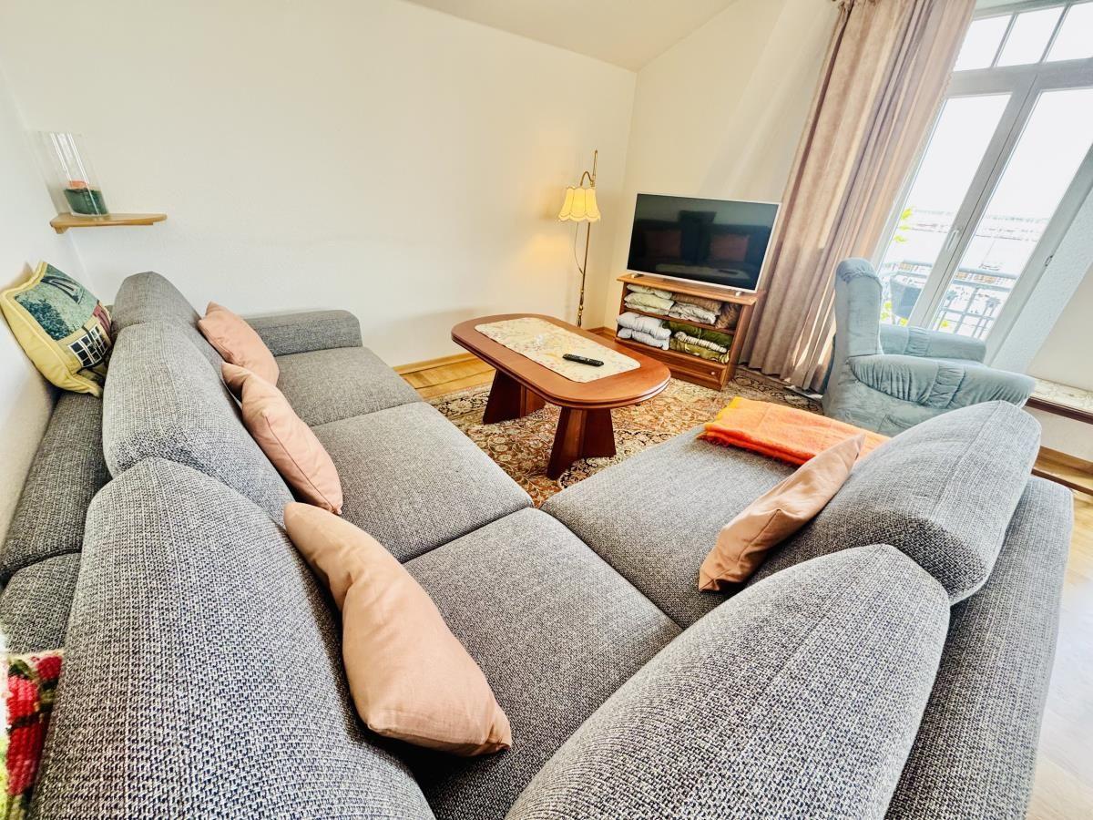 Wohn- und Essbereich mit Holzboden, Sofa, Esstisch und Küchenbereich.