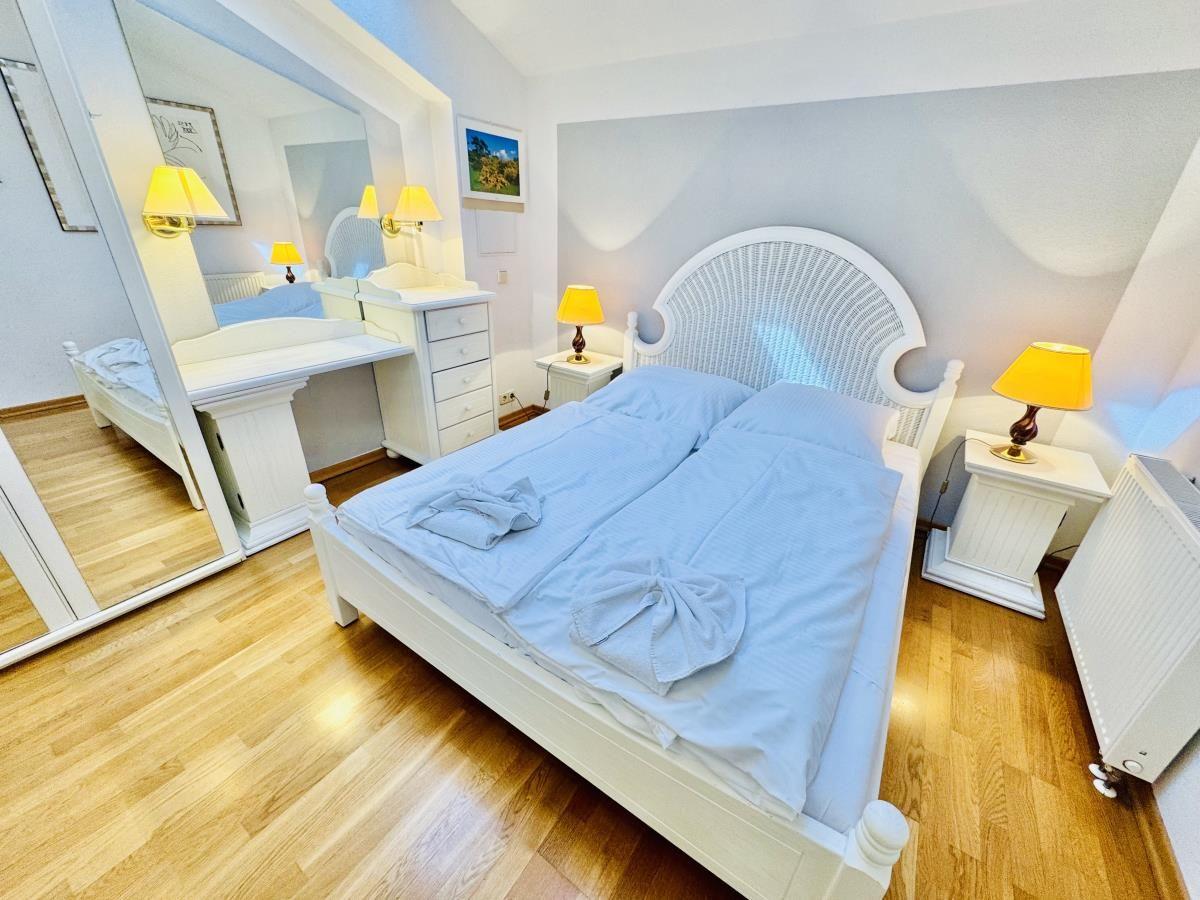 Ein Raum mit Holzboden, Sofa, Bücherregal und Stehlampe.