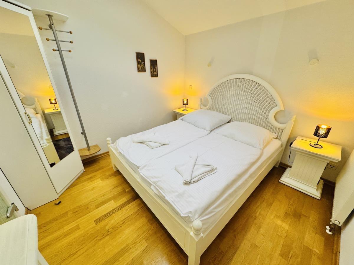 Badezimmer mit Waschmaschine, Toilette und Dusche. Fliesenboden und Spiegel.