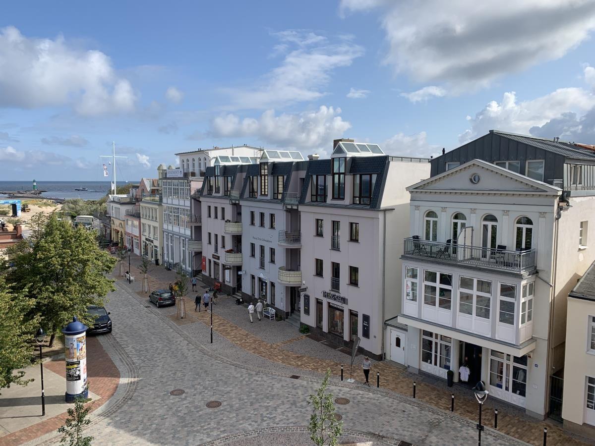 Leuchtturm neben Strand und modernen Gebäuden unter blauem Himmel.