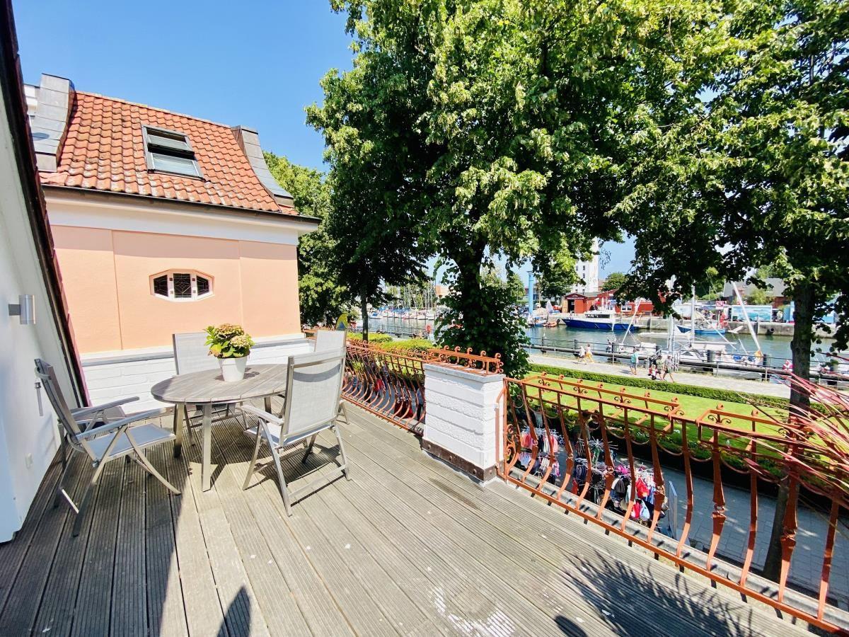 Wohnzimmer mit Sofa, Fernseher und Essbereich. Holzboden und große Fenster.