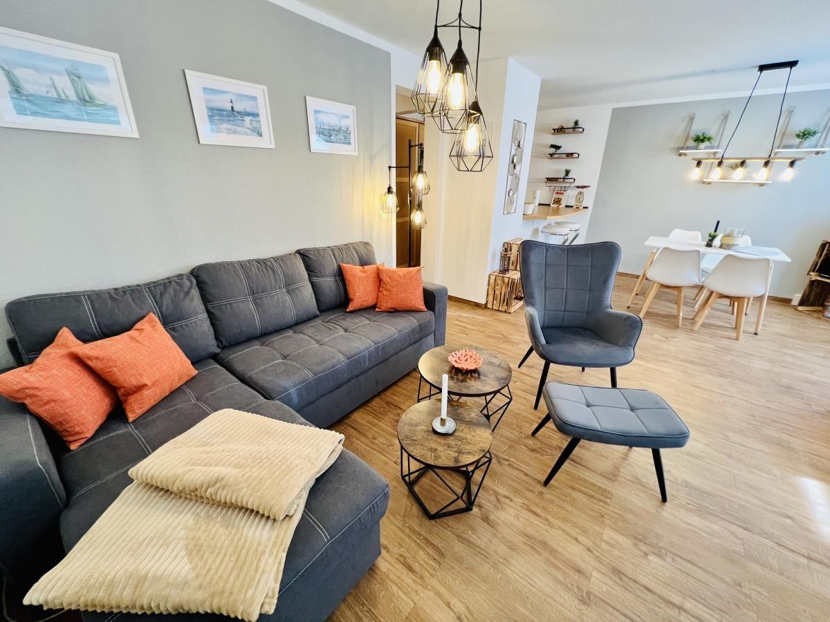 Wohnzimmer mit Sofa, Sessel, Fernseher und Holzboden.