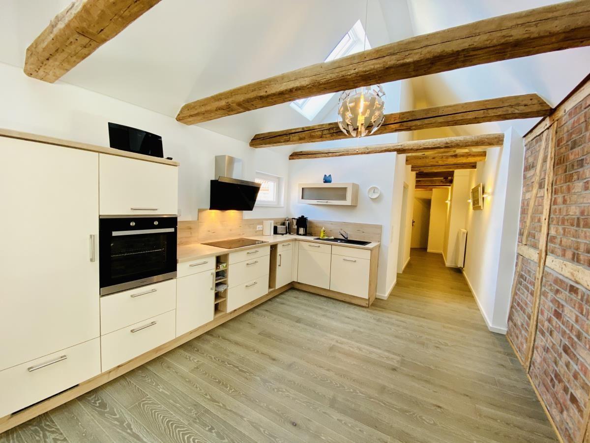 Esstisch mit sechs Stühlen, Holzboden und Backsteinwand im Essbereich.