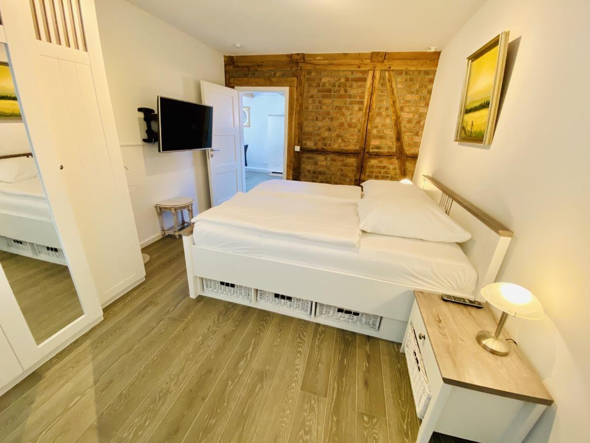 Badezimmer mit Dusche, Waschbecken und Toilette. Holzbalken und dunkle Fliesen.