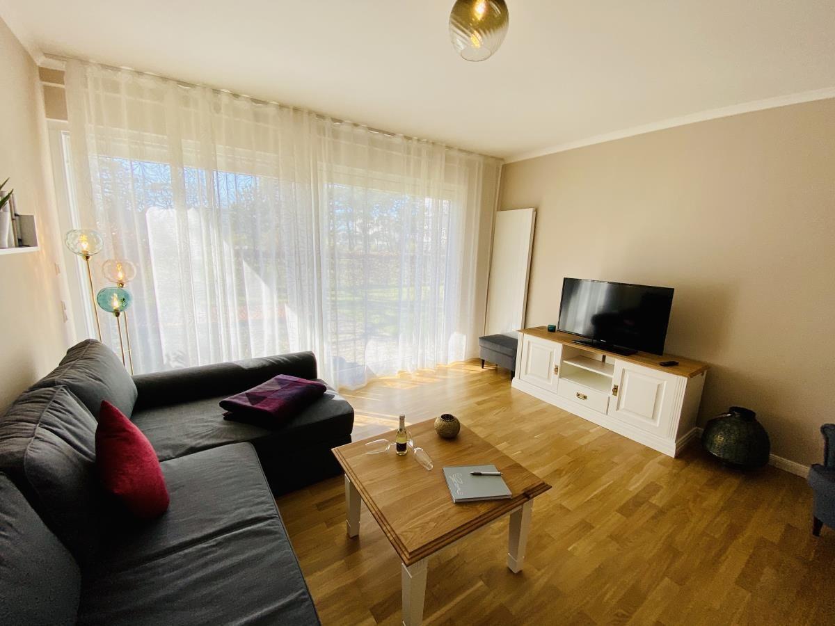 Küche mit Essbereich, weiße Schränke, Holzfußboden und Esstisch mit Stühlen.