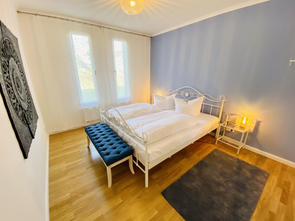 Schlafzimmer mit Doppelbett, blauem Sitzbank und Kleiderschrank