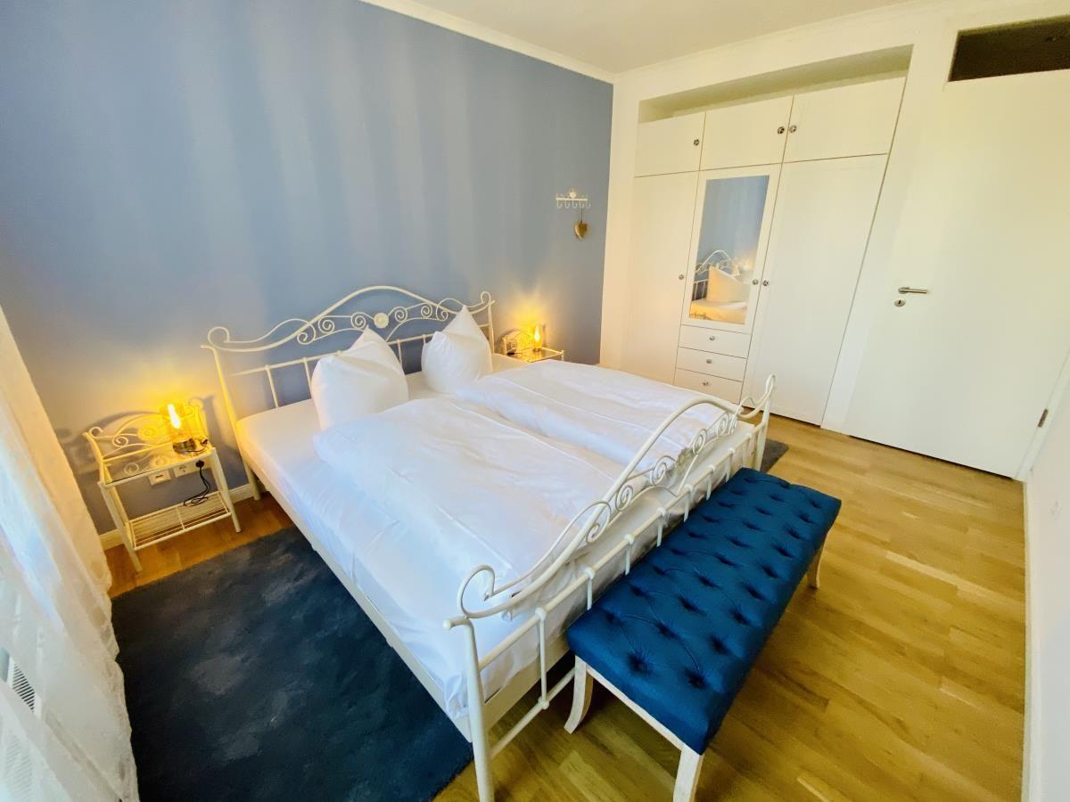 Flur mit Holzboden, Wandbild und Tür zum Bad mit Musterwand.