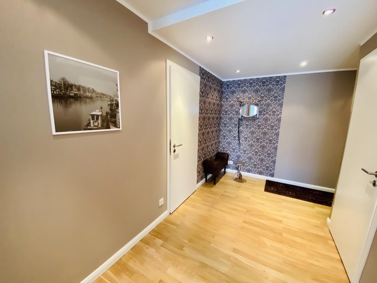 Flur mit Holzboden, blau gemusterter Wand und brauner Ledercouch