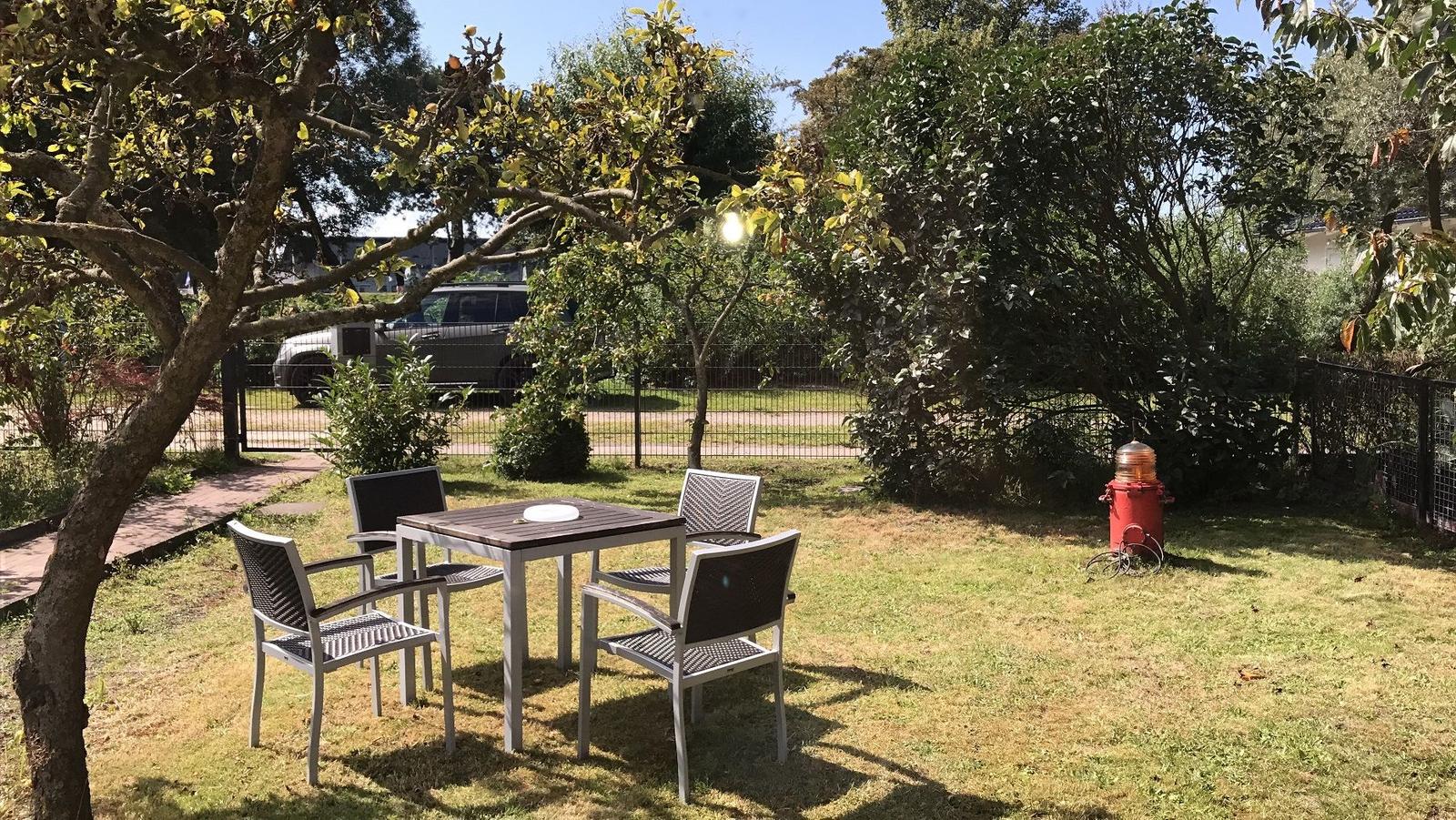 Wohnzimmer mit Sofa, Glas-Tisch und Fernseher. Holzfußboden und Fenster mit Blick.