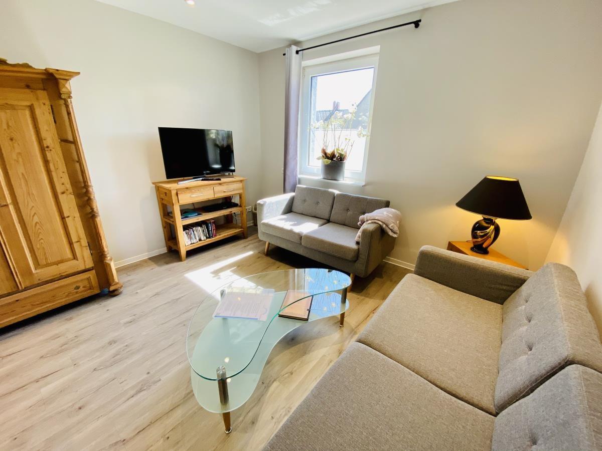 Esszimmer mit Holztisch und Stühlen, Küche mit grünen Schränken und Küchengeräten.