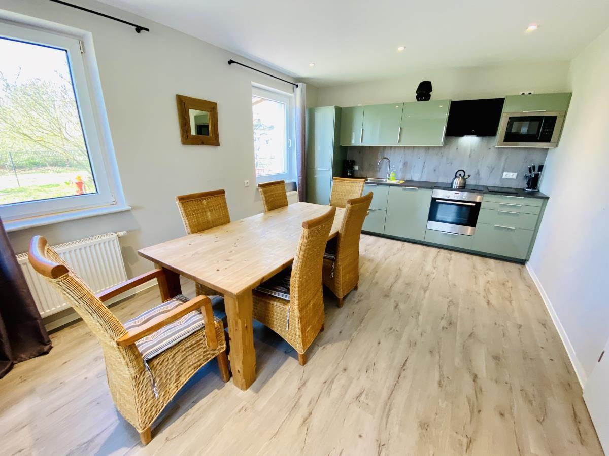 Moderne Küche mit grünen Schränken, Edelstahlgeräten und Holzfußboden.