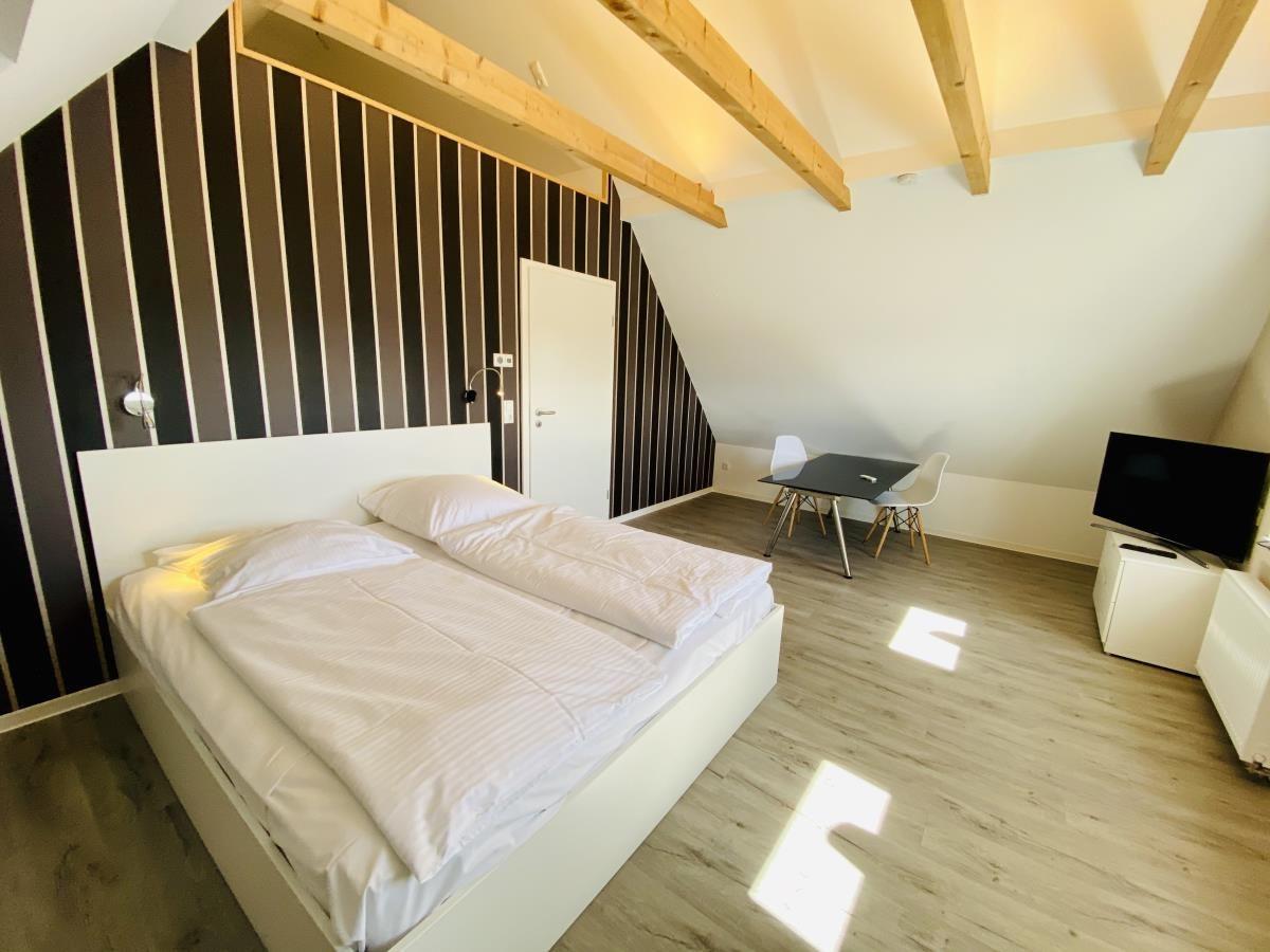 Ein Schlafzimmer mit Doppelbett, Schreibtisch und Fernseher an der Wand.