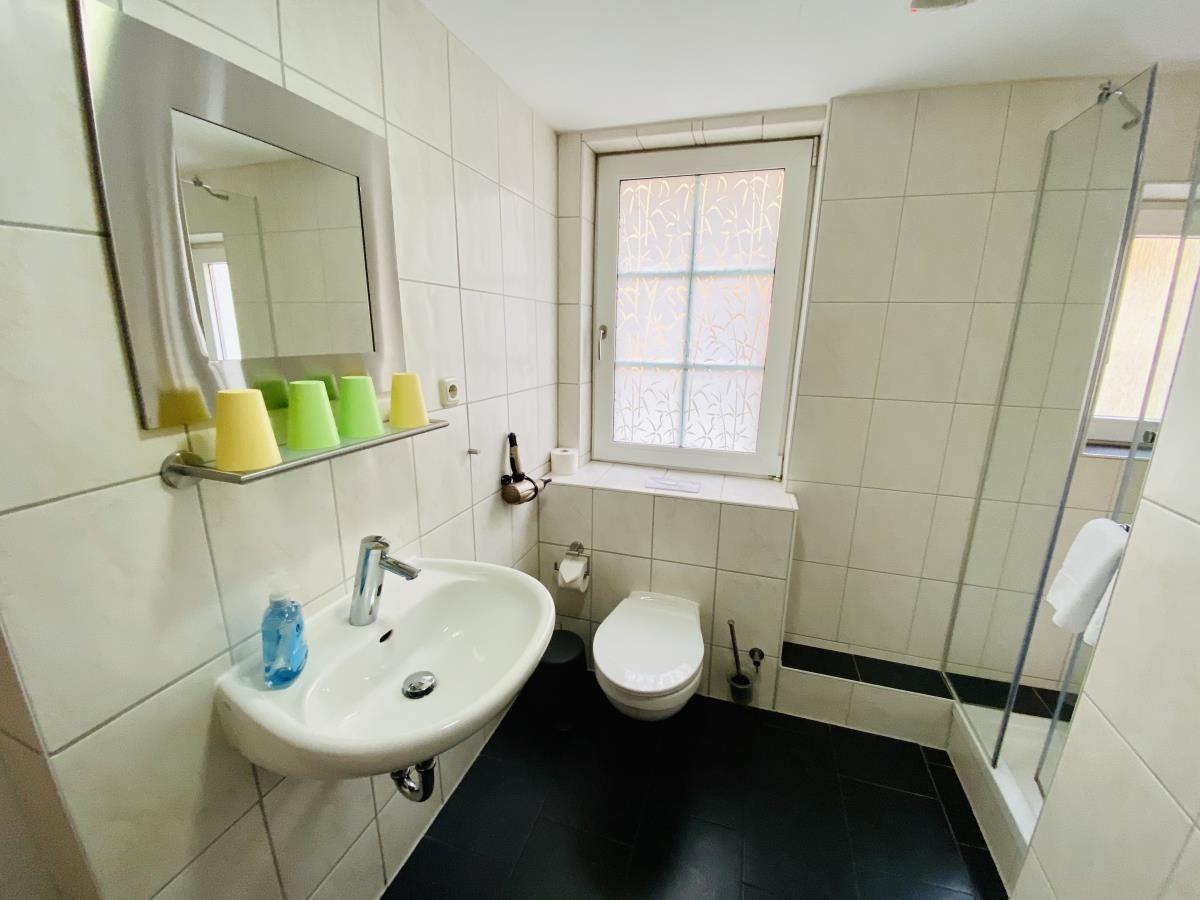 Dusche mit Glaswand, Handtuchhalter und blauer Bank.